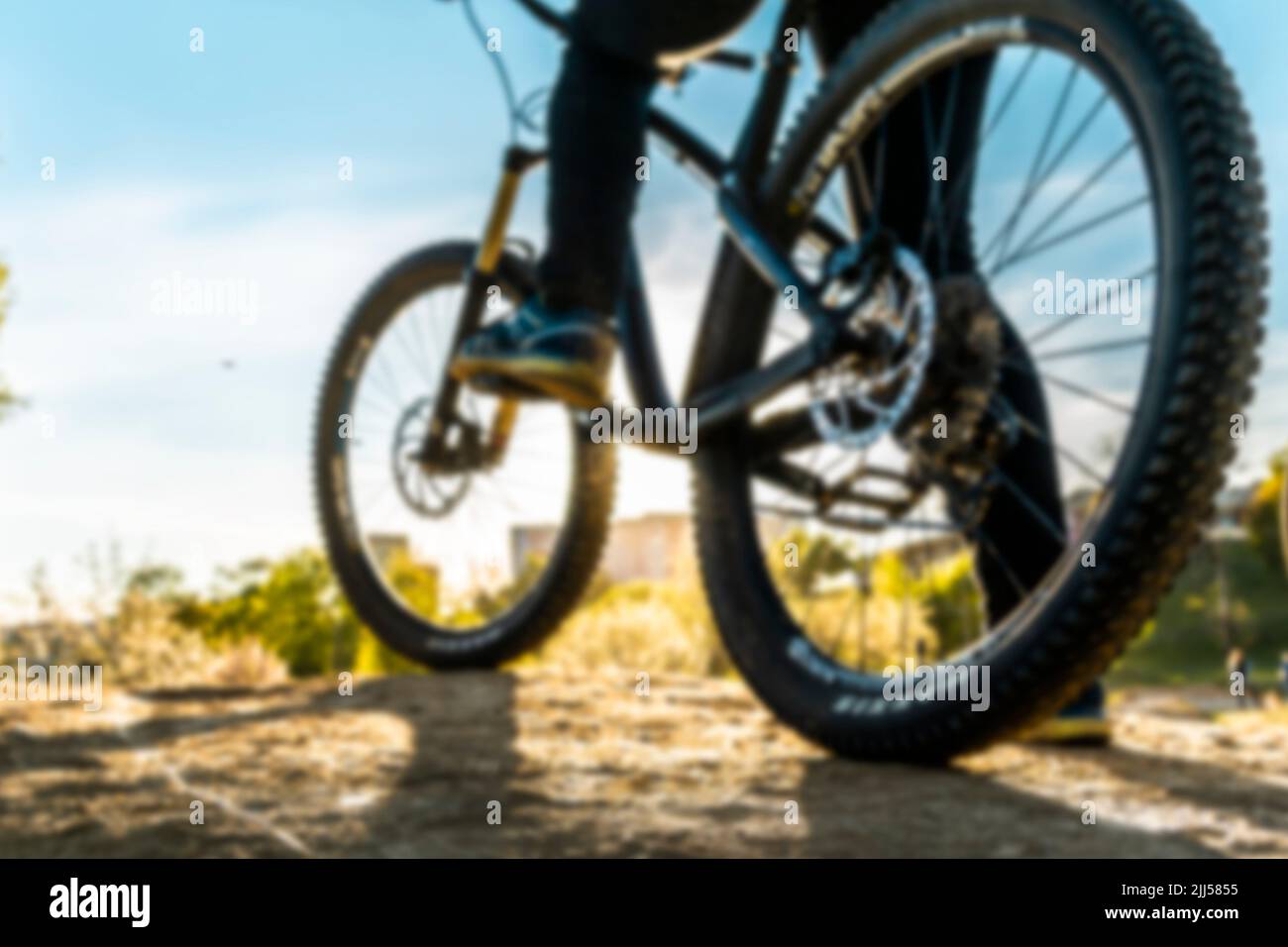 Foot on bike pedal at sunset. Close up rear view cyclist pedalling. Bicycle on the road. Stock Photo