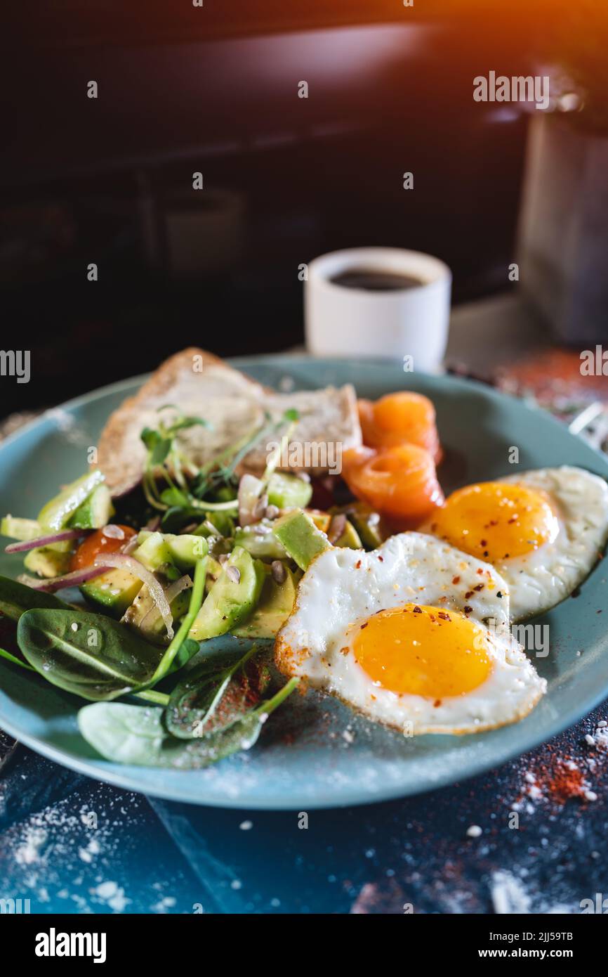 fresh breakfast with fried eggs, bread, avocado, red fish salmon and