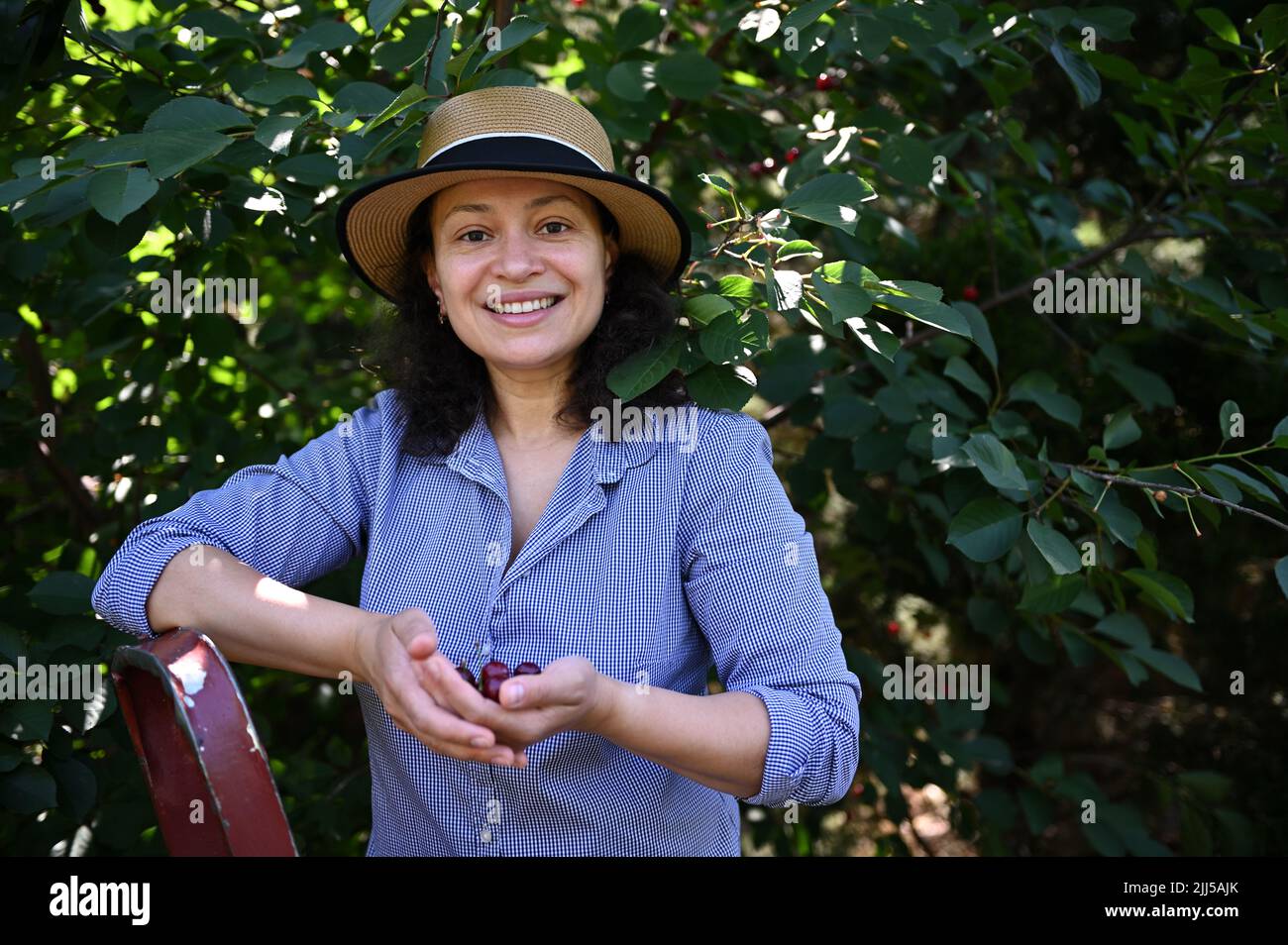 Portrait of a female farmer in a straw hat, smiles looking at camera ...
