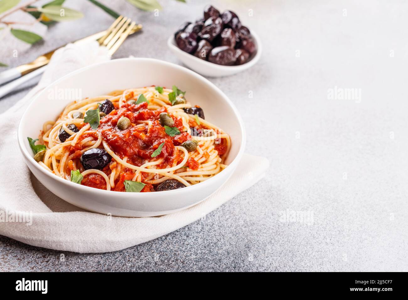 Spaghetti alla puttanesca . Italian pasta with tomatoes, olives, capers, anchovies and parsley. Italian food. Copy space Stock Photo