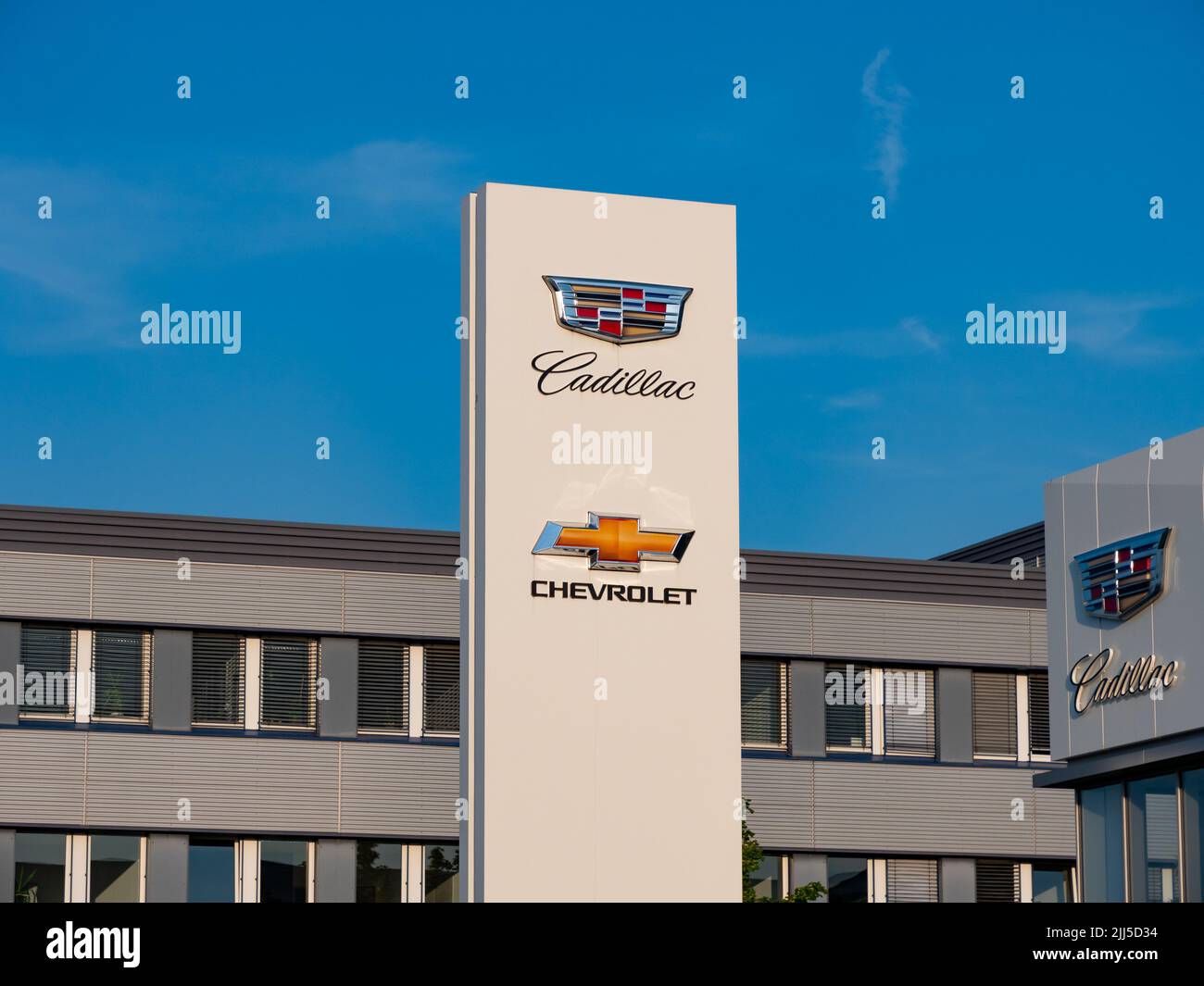 Logos of the American automotive brands Cadillac and Chevrolet in front of a car dealer. Signs in front of a building exterior of a showroom. Stock Photo