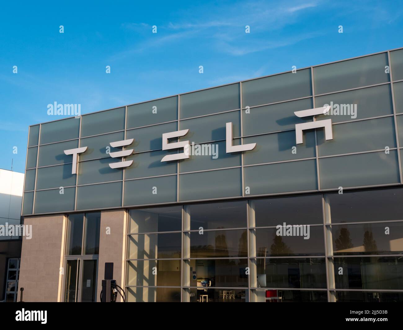 Tesla Inc. lettering on the facade of a building exterior. Tesla showroom of the American automotive company. A famous manufacturer of electric cars. Stock Photo