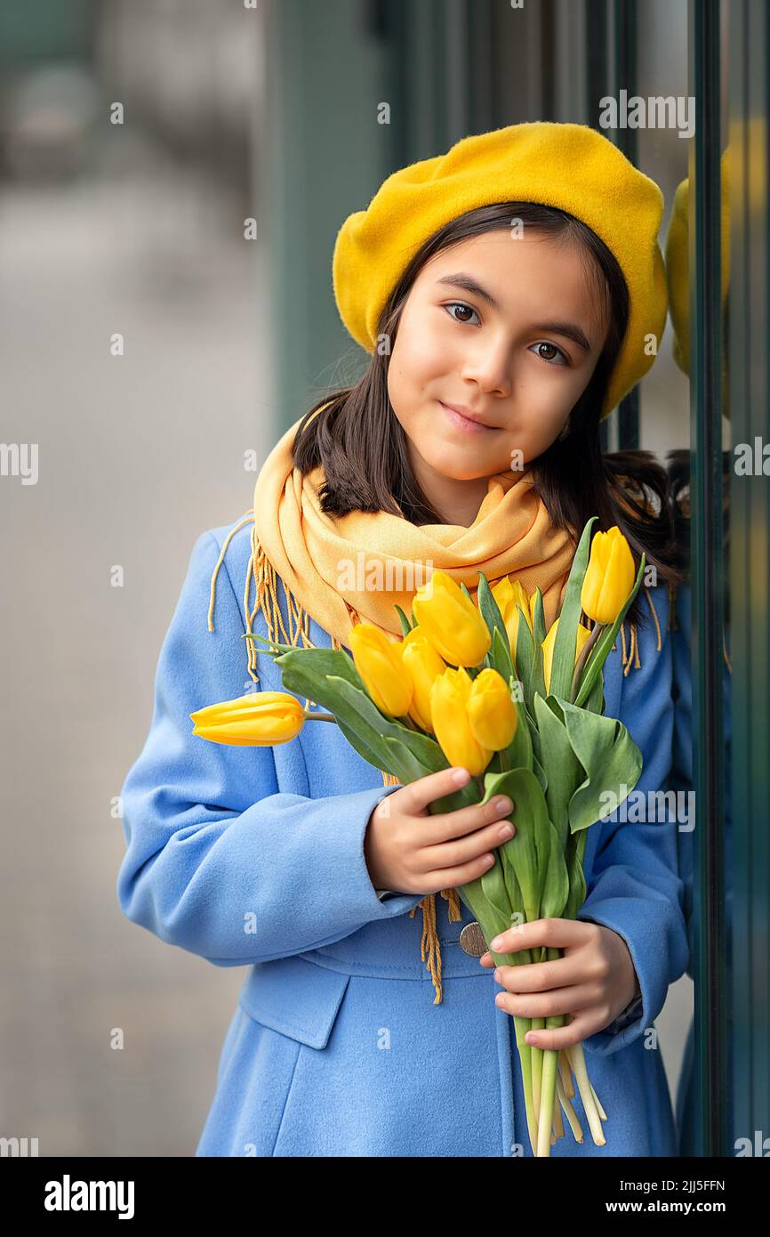 Portrait of a happy girl with a bouquet of yellow tulips on a walk in spring. Flowers for International Women's Day. Stock Photo