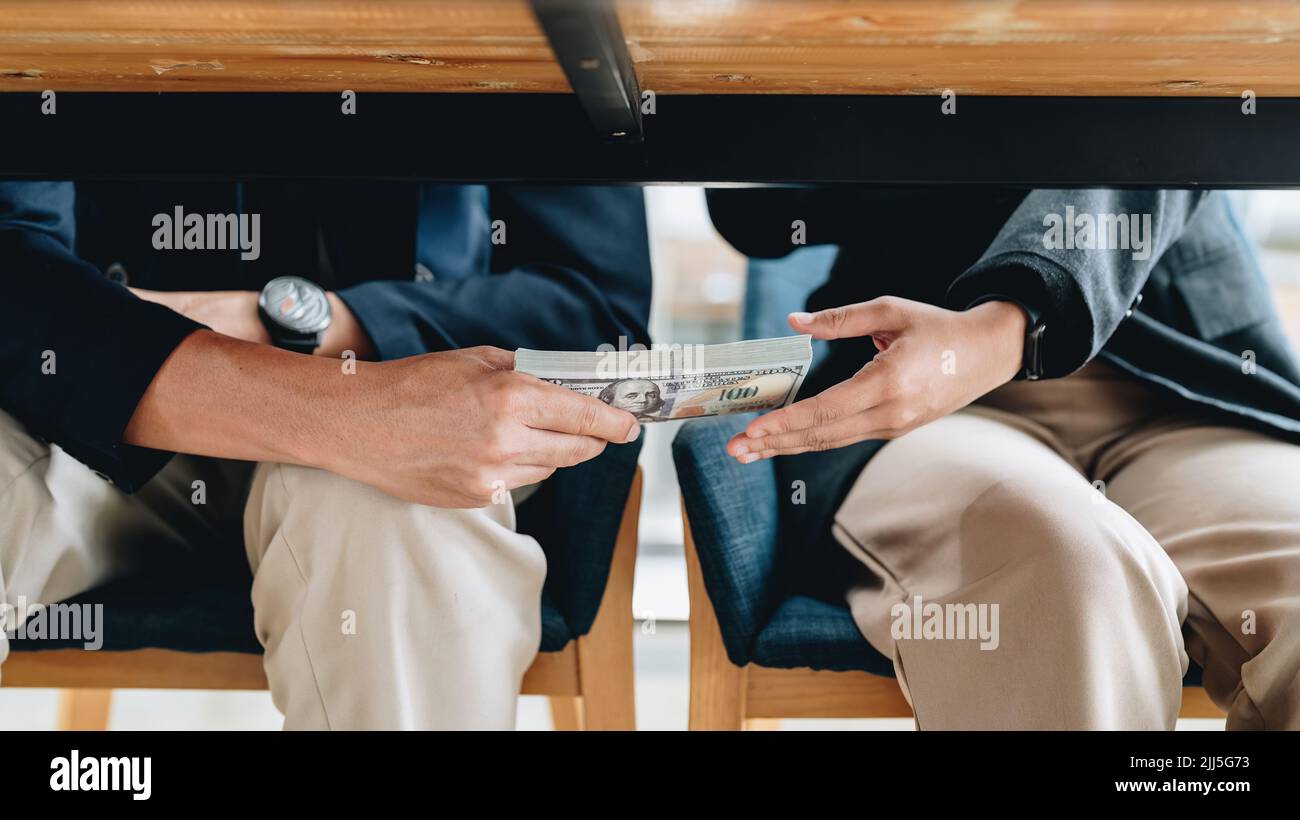 Hands passing money under table corruption bribery concept Stock Photo
