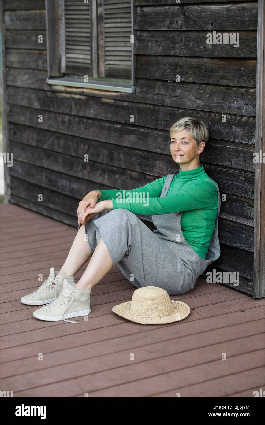 Thoughtful woman sitting on porch Stock Photo