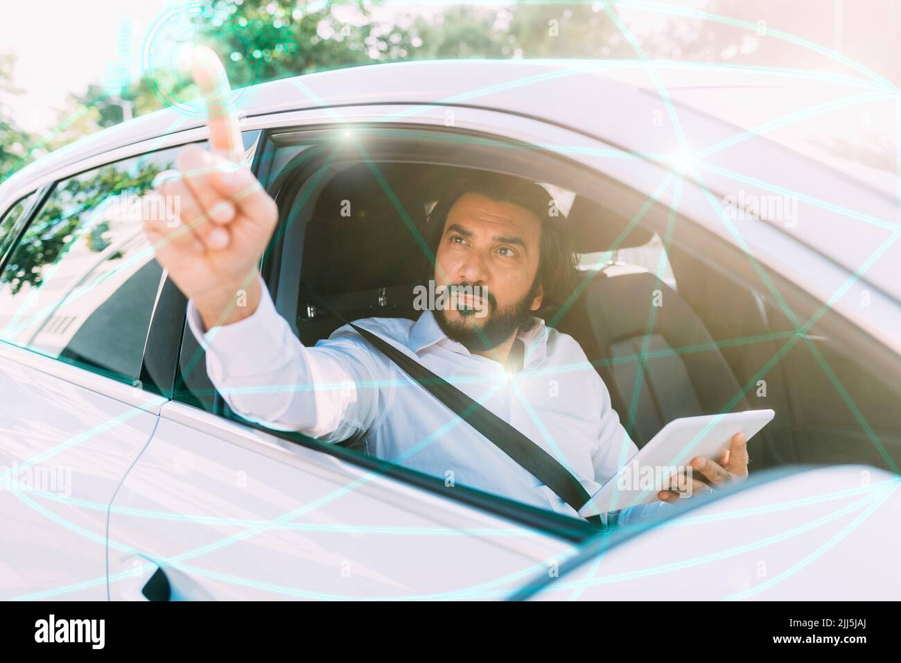 Mature man using tablet PC on virtual screen sitting in car Stock Photo