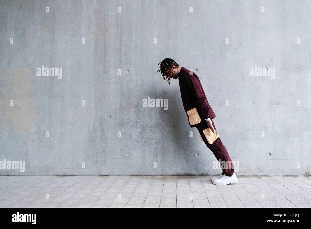 Young man leaning in front of concrete wall Stock Photo - Alamy