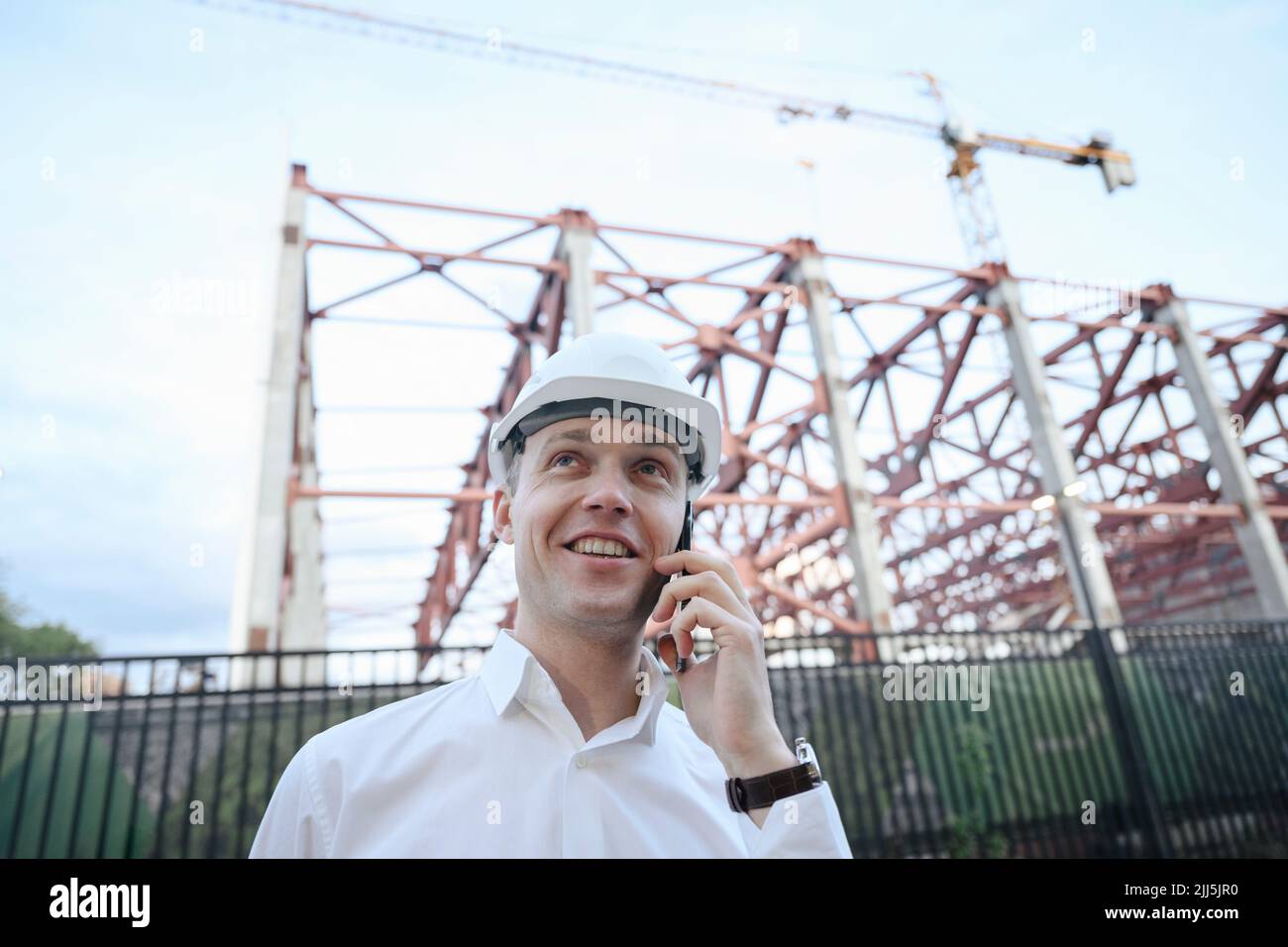 Happy engineer talking on smart phone at construction industry Stock Photo