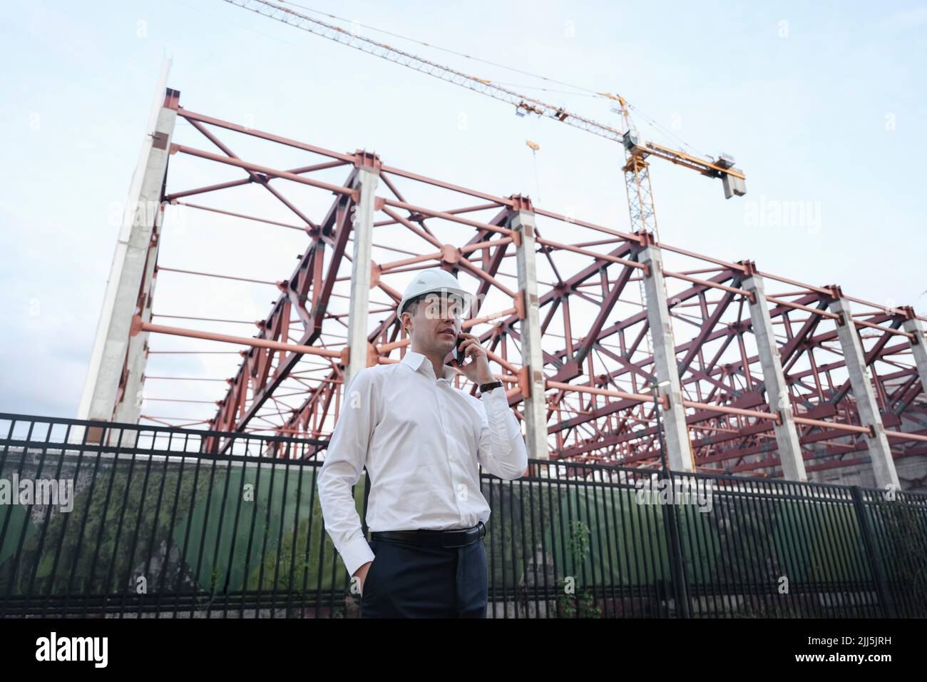 Engineer talking on smart phone standing at construction site Stock Photo