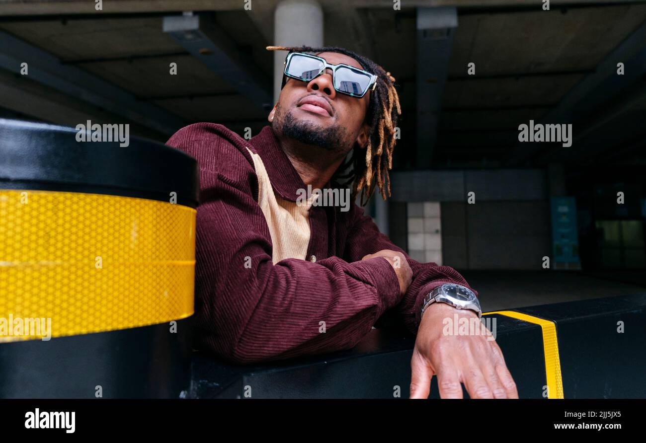 Man looking up wearing sunglasses by wall Stock Photo