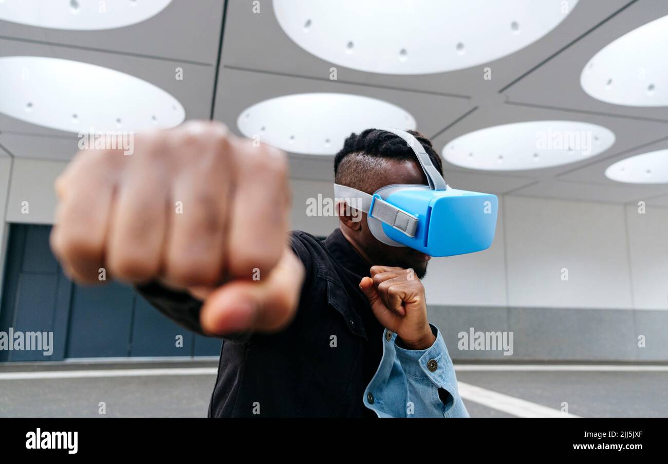 Man boxing wearing virtual reality headset under illuminated ceiling