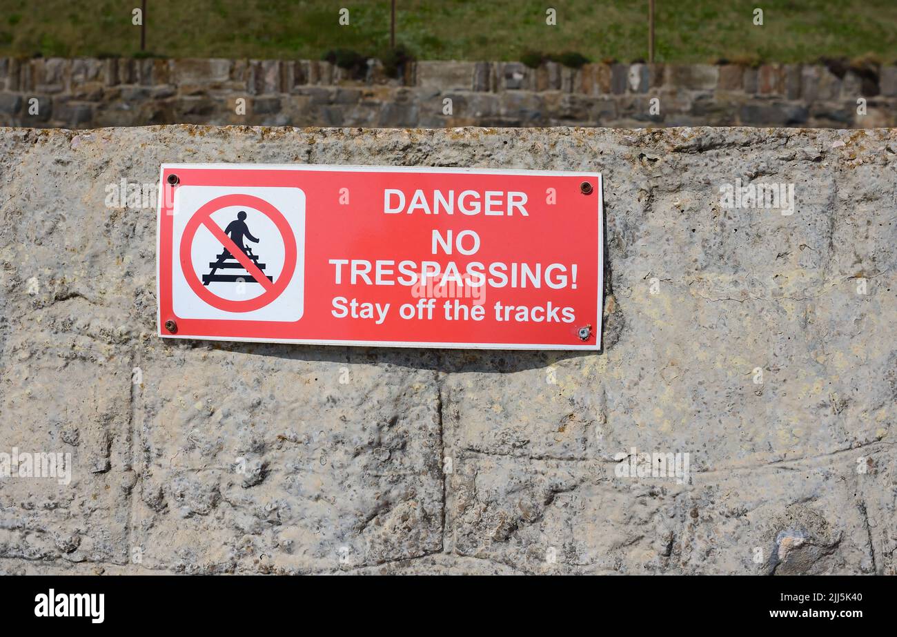 Danger No Trespassing sign on the wall alongside the railway at Dawlish, South Devon. Stock Photo