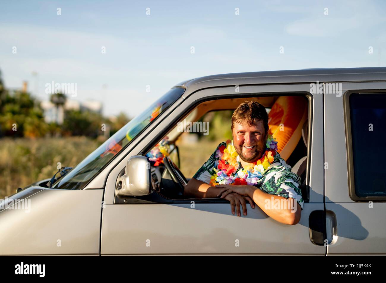 Smiling man looking through car window Stock Photo