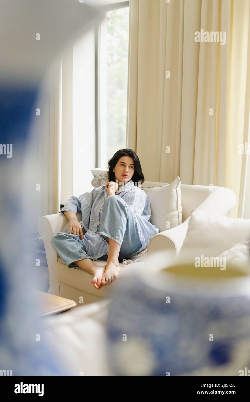 Woman sitting on sofa at home Stock Photo