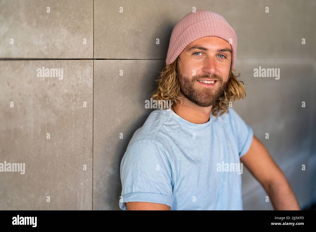 Smiling man wearing knit hat by wall Stock Photo