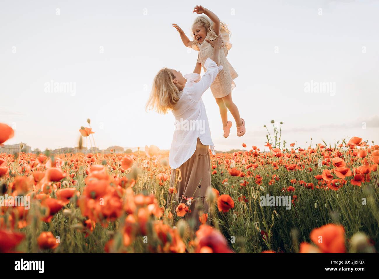 Playful mother lifting daughter in air on sunny day Stock Photo