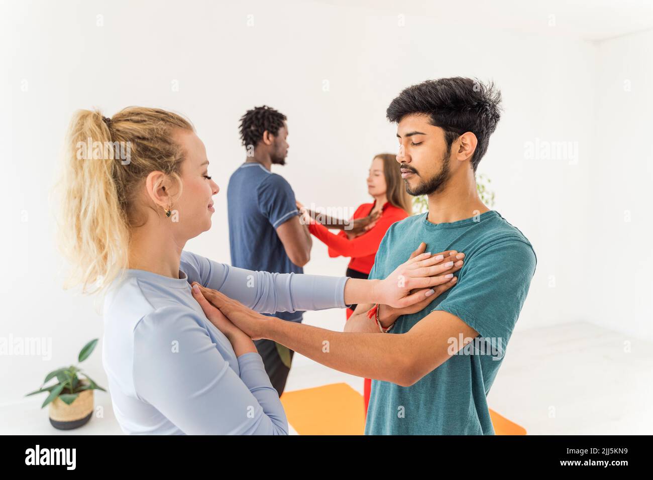 Couples with eyes closed touching chest of each other at yoga studio Stock Photo