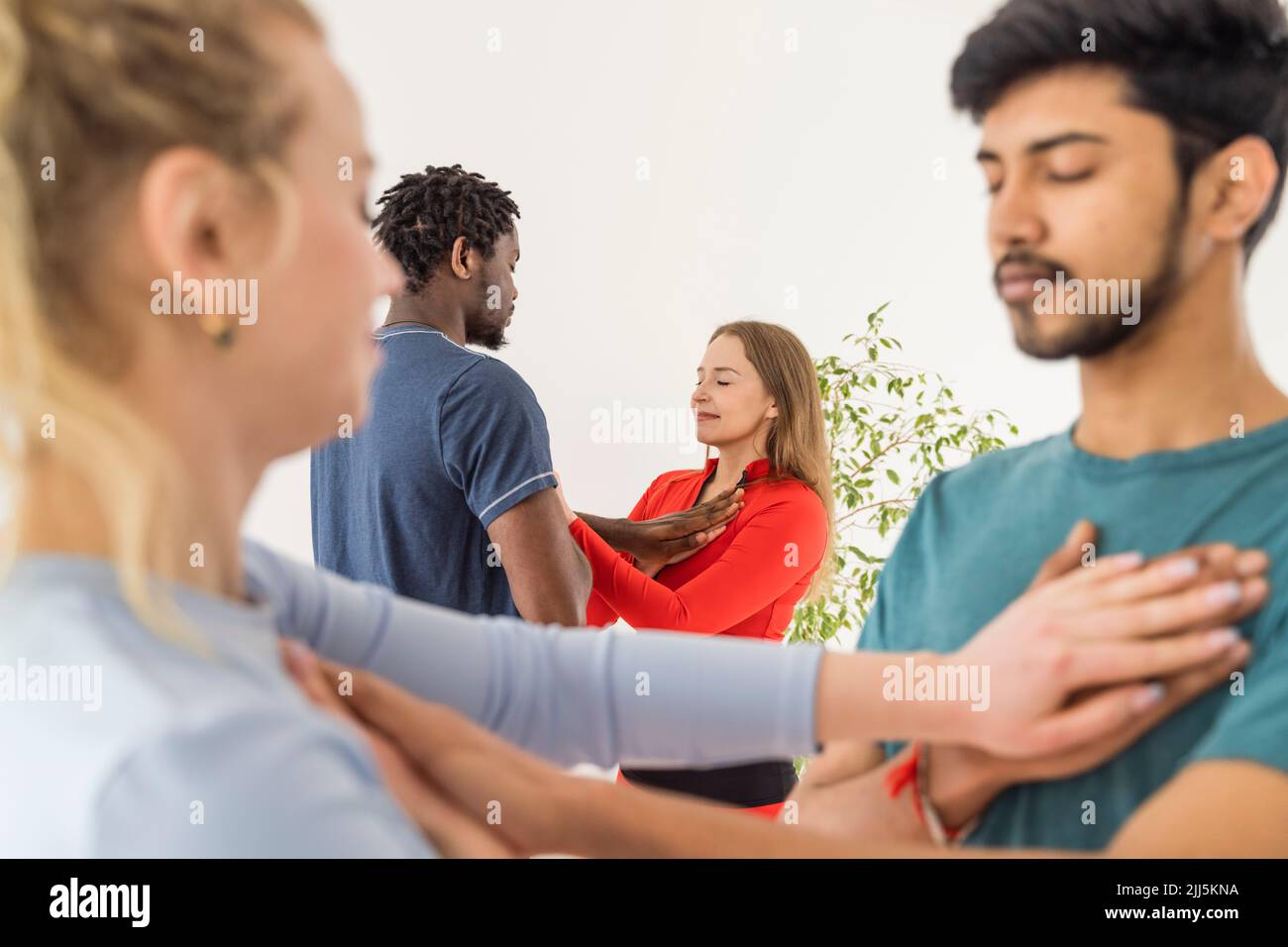 Couples with eyes closed touching chest of each other practicing yoga in class Stock Photo
