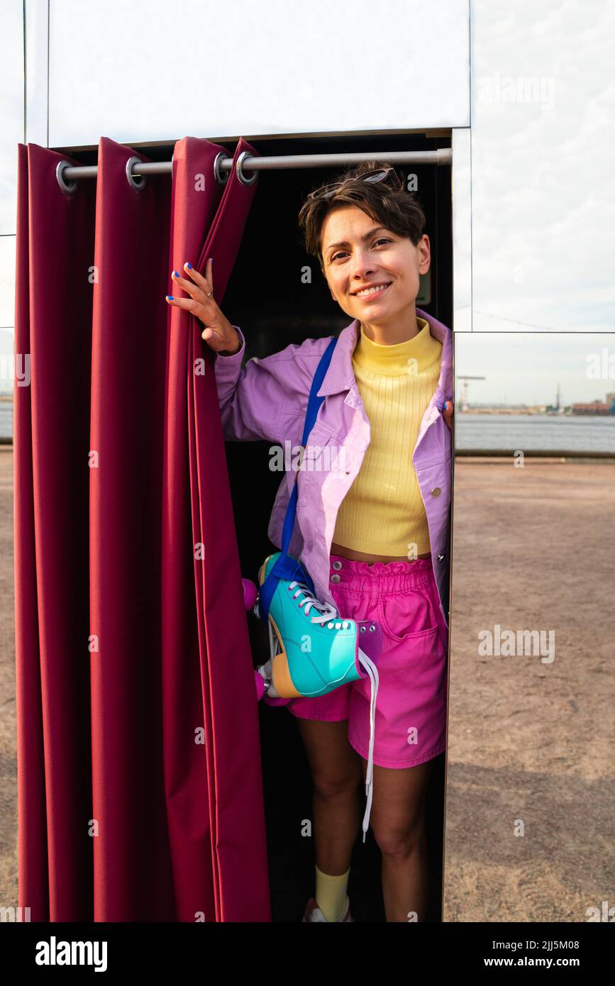 Happy woman with roller skates standing in photo booth Stock Photo