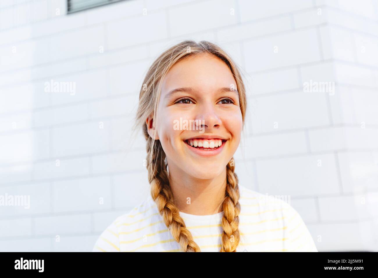 Happy girl standing in front of wall Stock Photo - Alamy