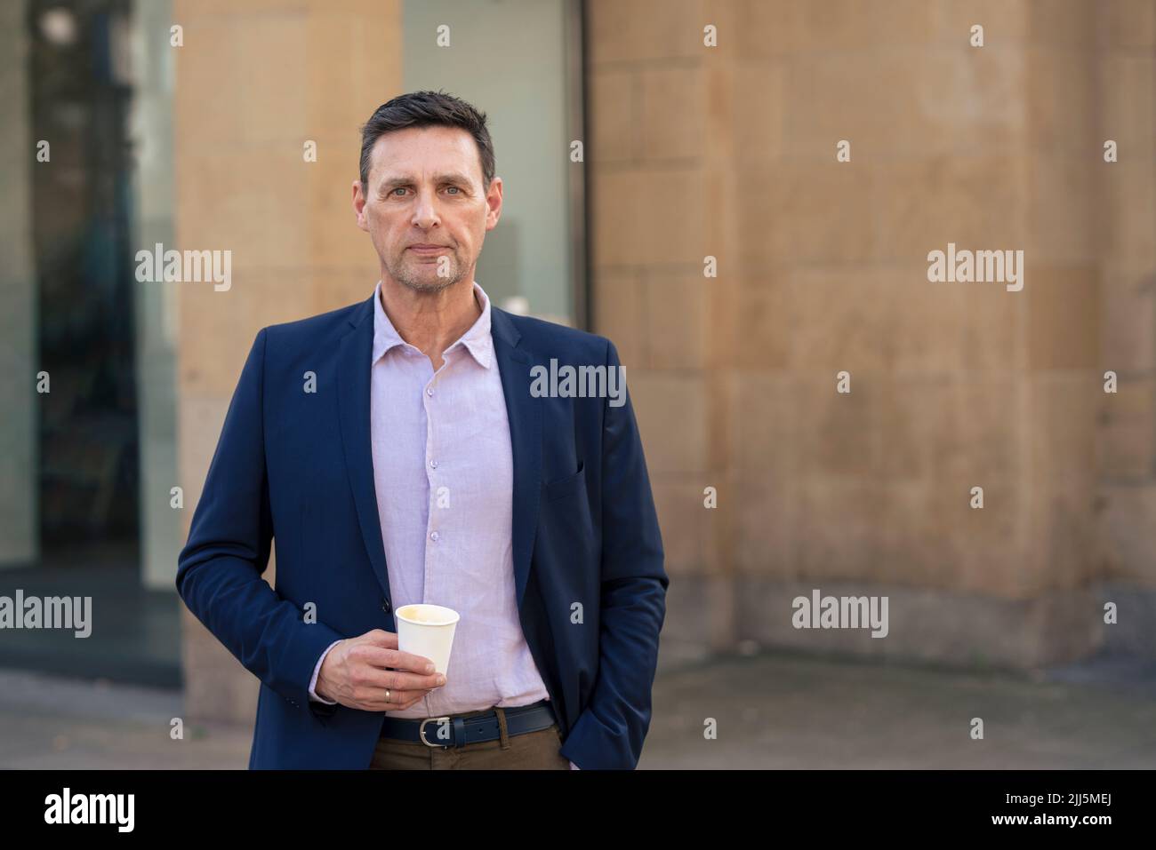 Confident businessman holding disposable cup Stock Photo