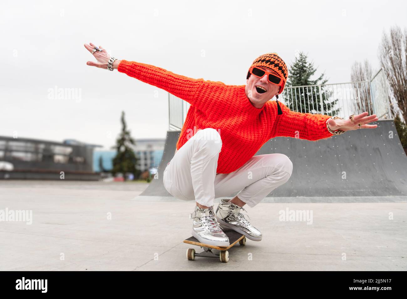 Happy mature man with arms outstretched enjoying on skateboard Stock Photo