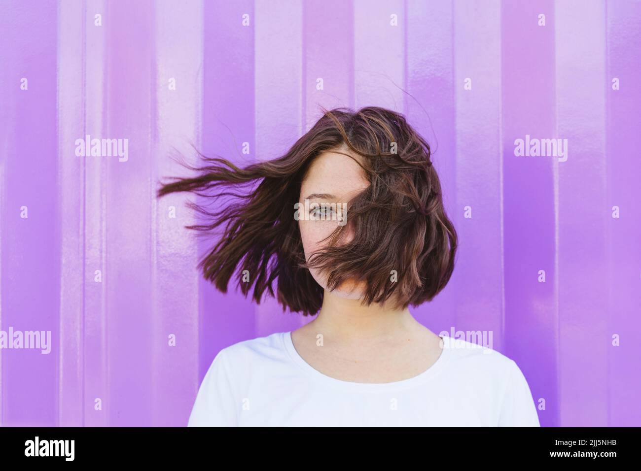 Teenage girl with tousled hair in front of purple cargo container Stock