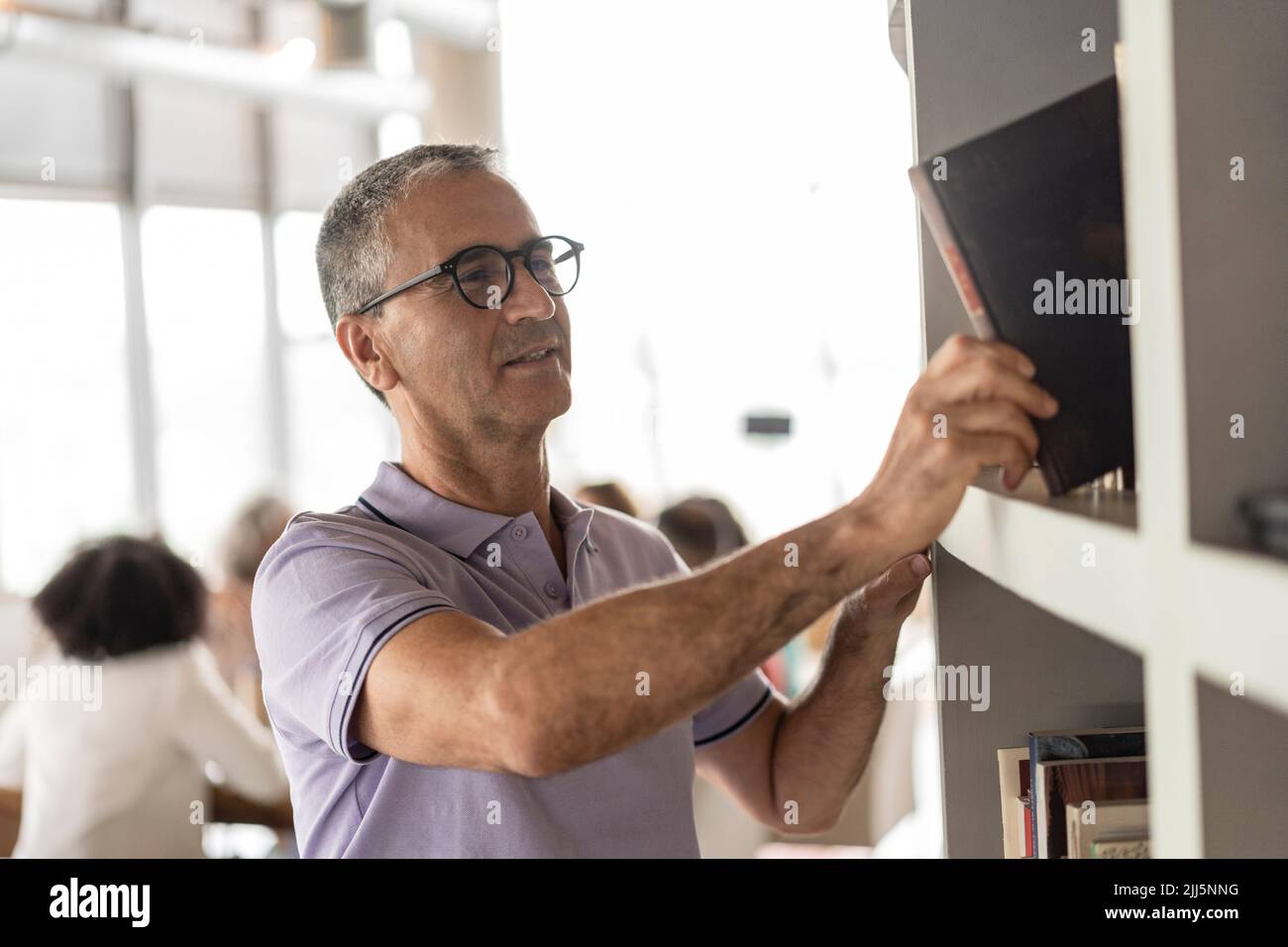 Businessman stacking file in rack at office Stock Photo