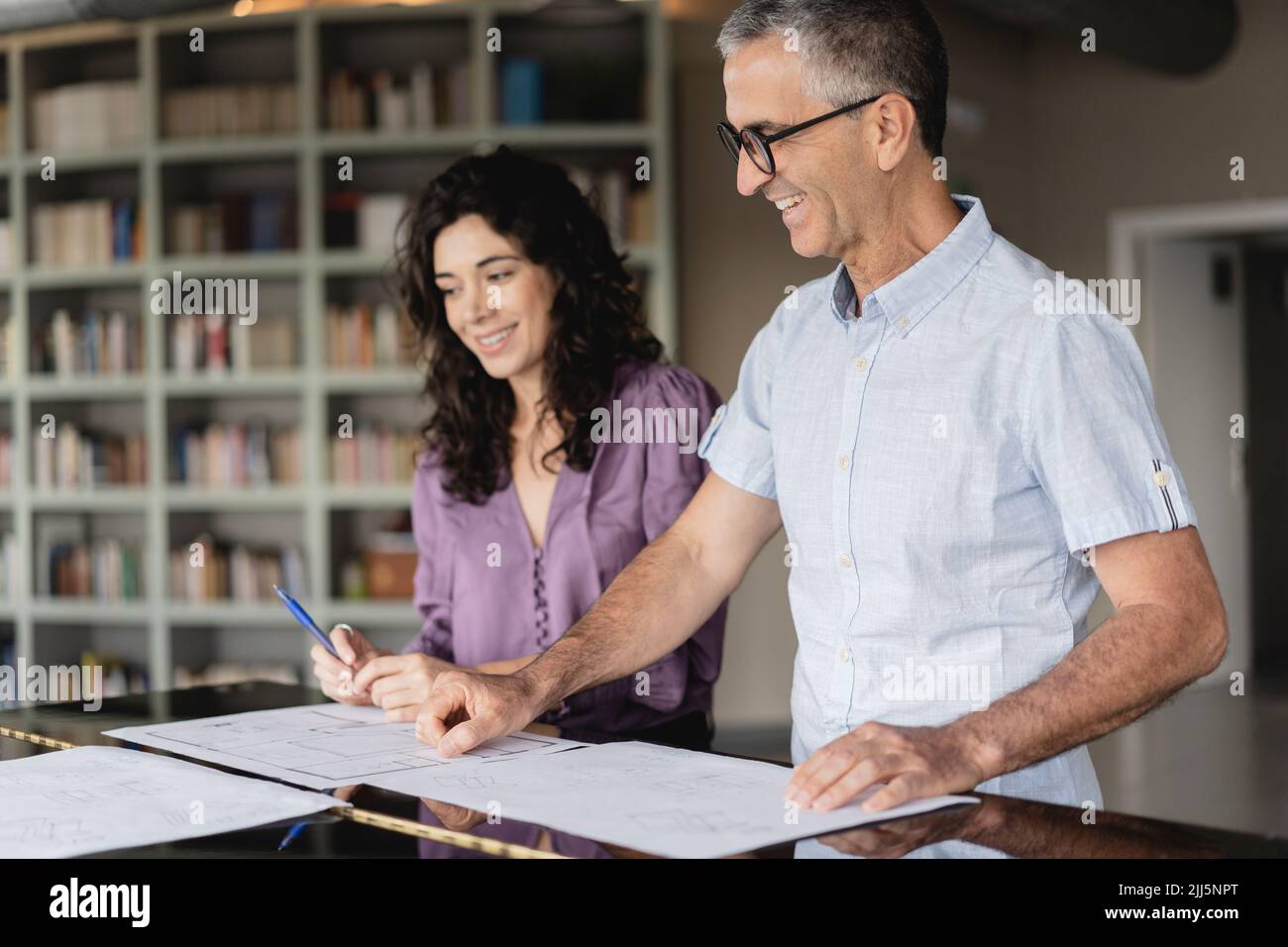 Smiling colleagues looking at business plan on table at office Stock Photo