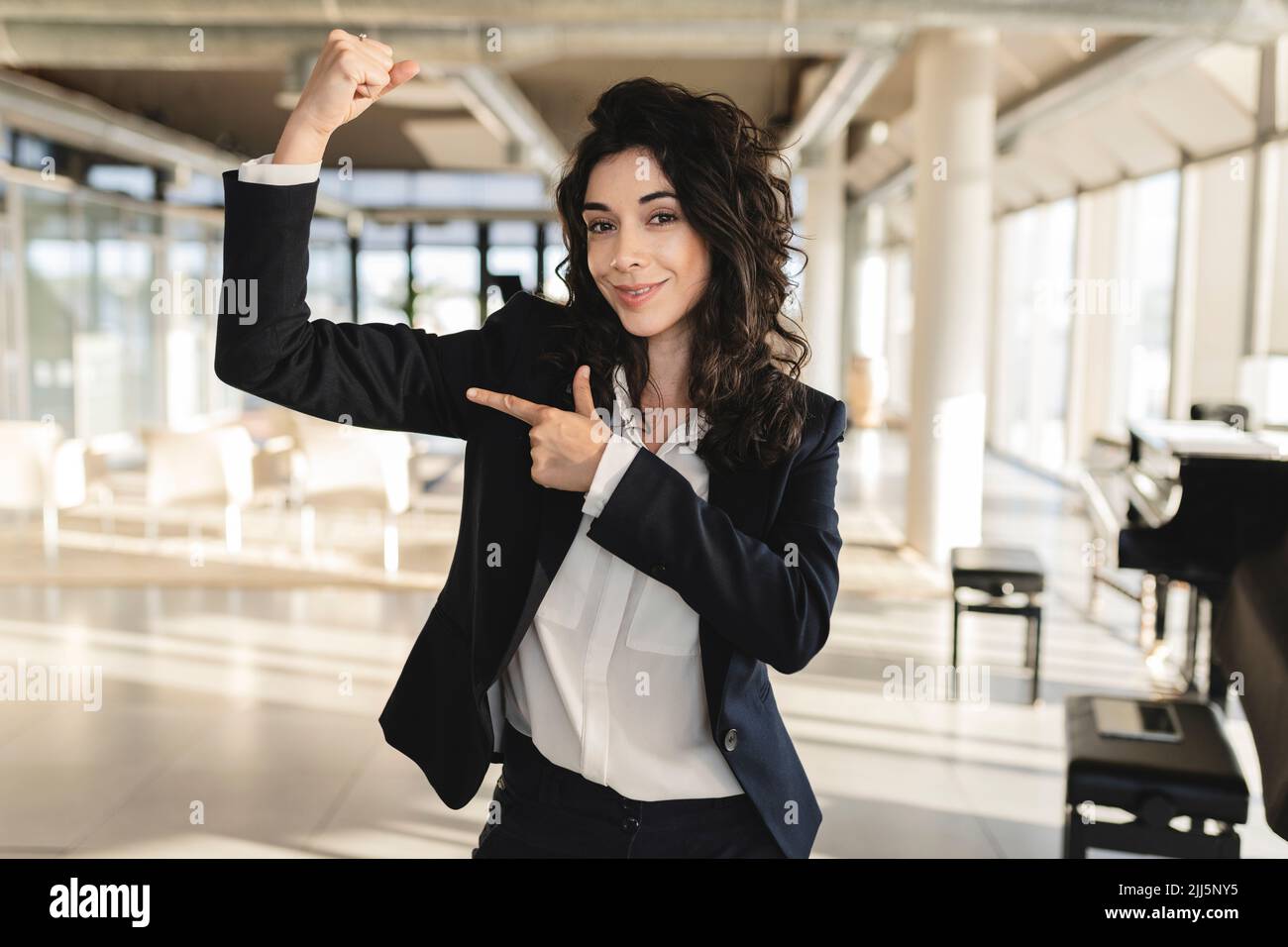 Businesswoman pointing at muscle in office Stock Photo
