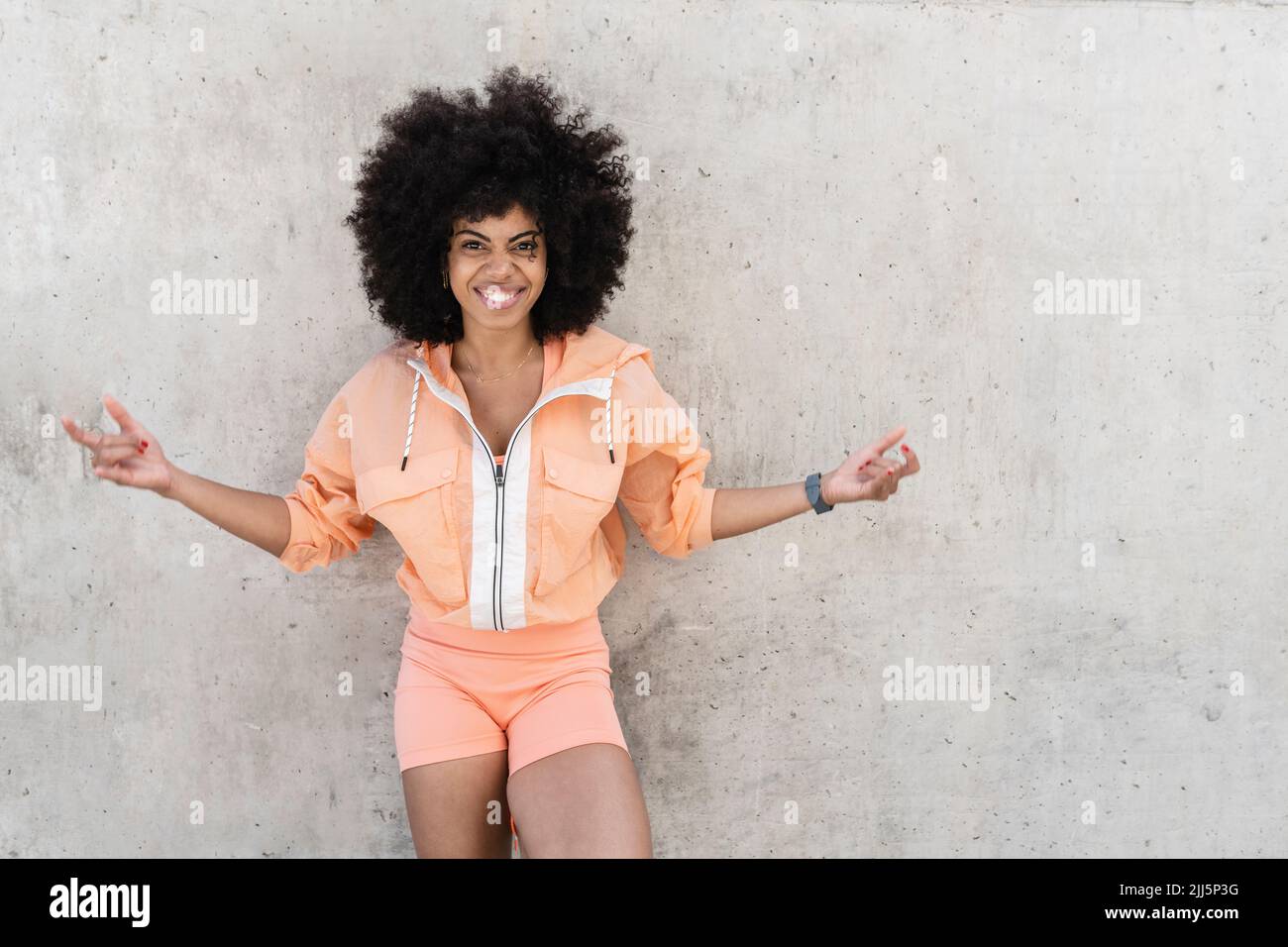 Happy woman standing in front of wall Stock Photo - Alamy