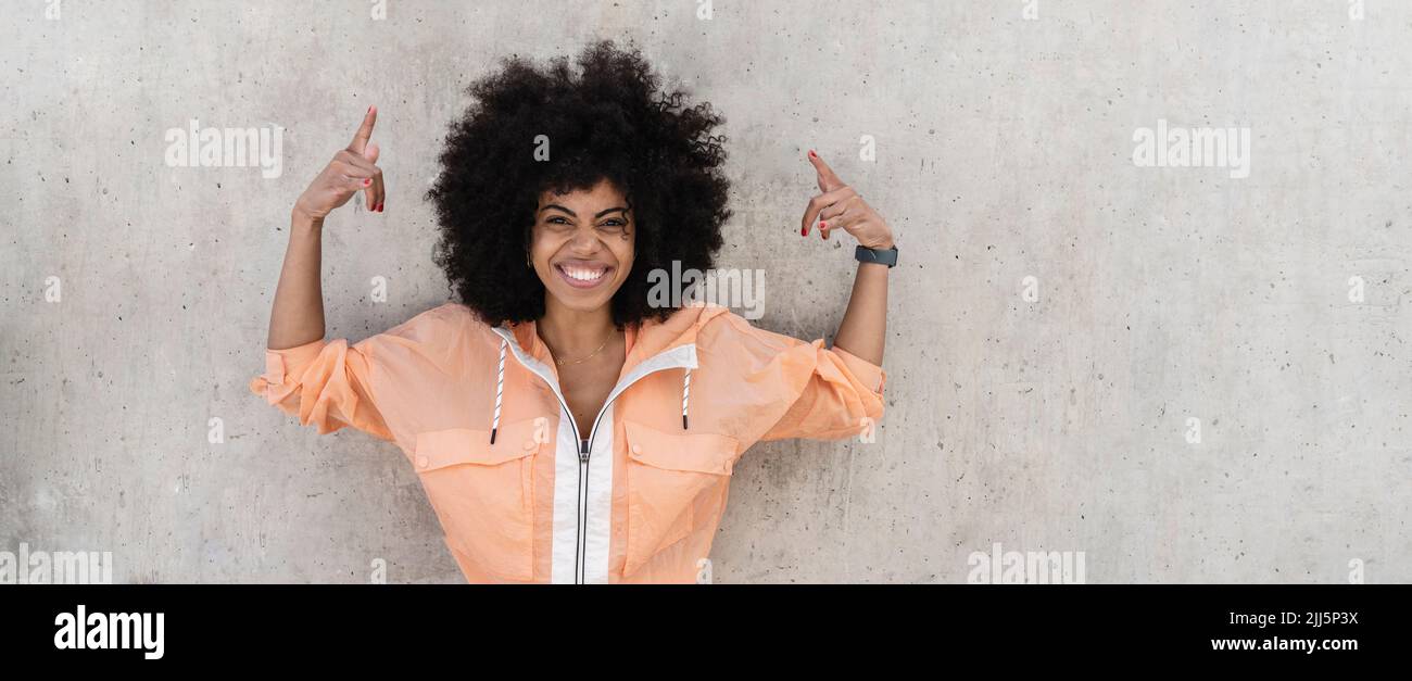Happy Afro sports woman gesturing in front of wall Stock Photo - Alamy