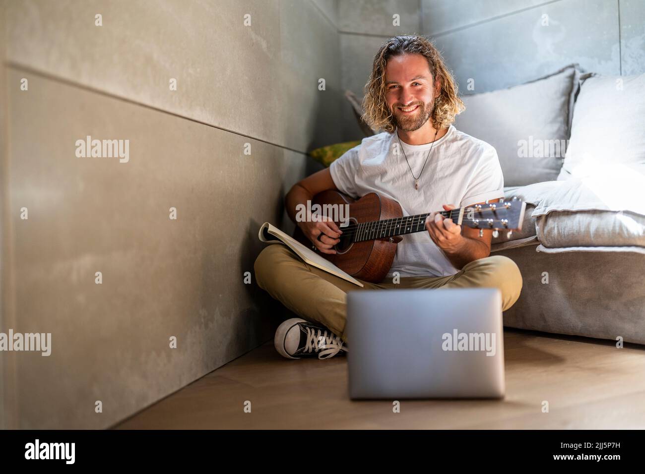 Smiling composer playing guitar at home Stock Photo