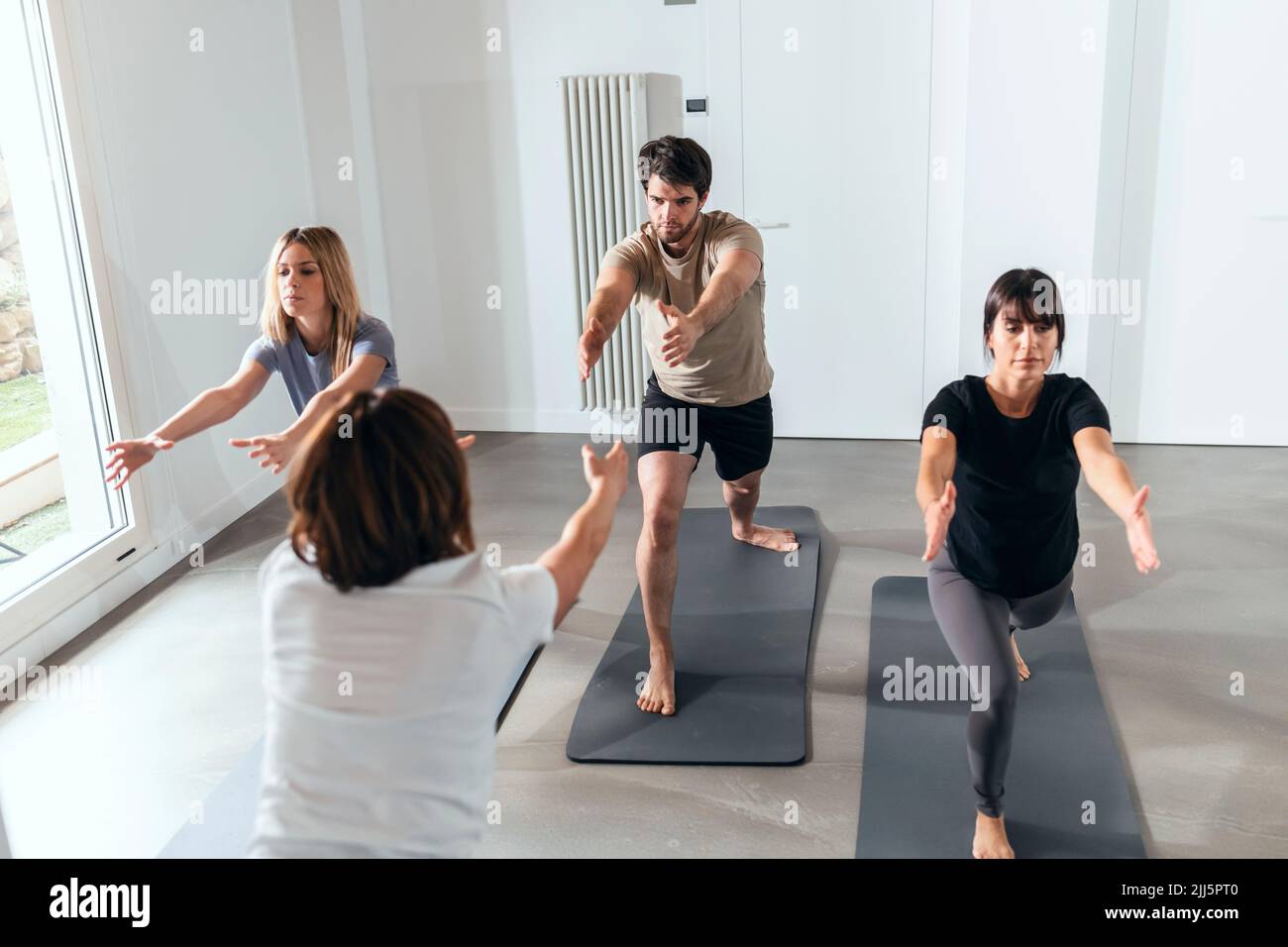Man and women practicing yoga in exercise class Stock Photo