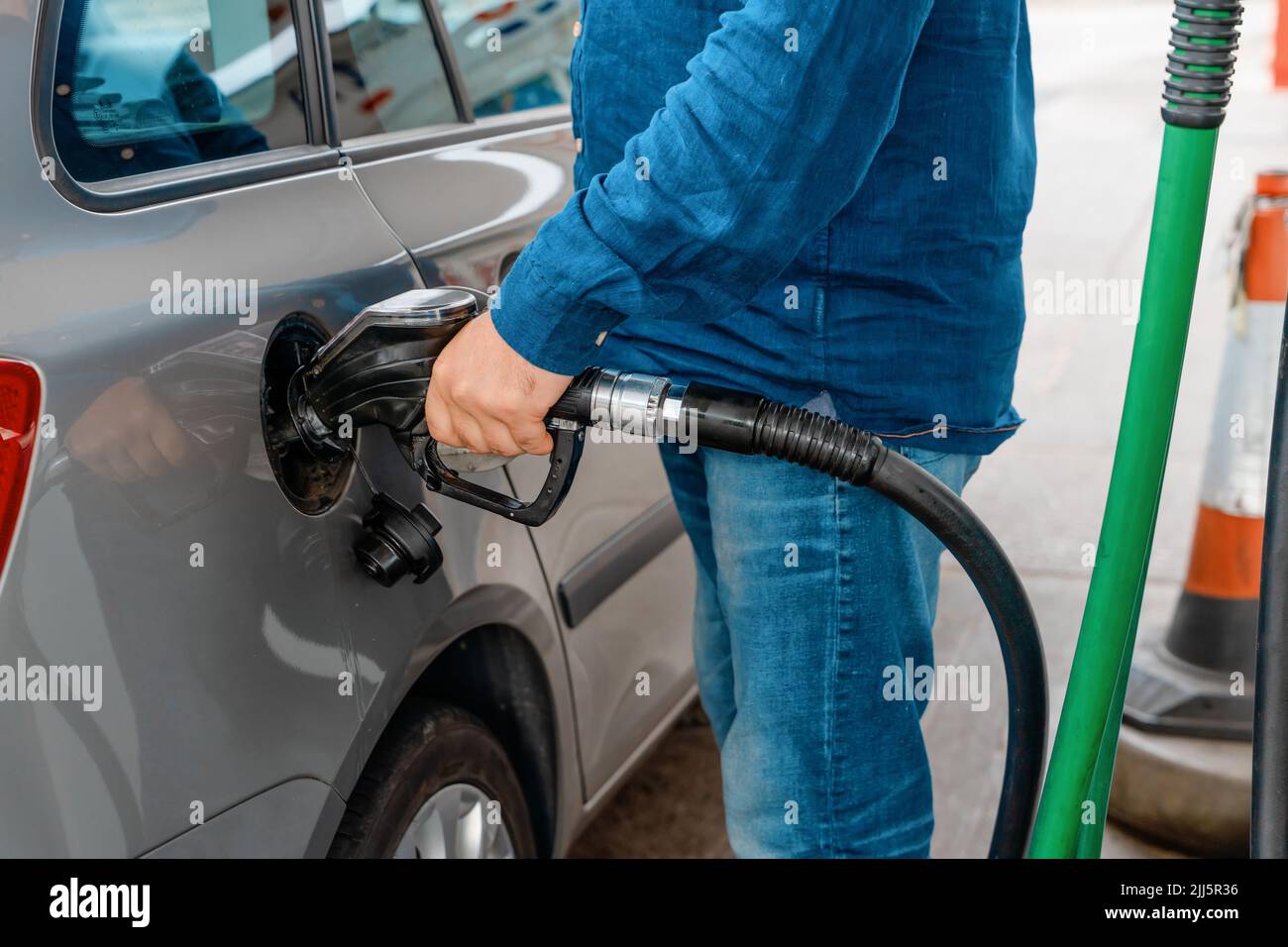 A man at the gas station filling the tank of his car with diesel to the