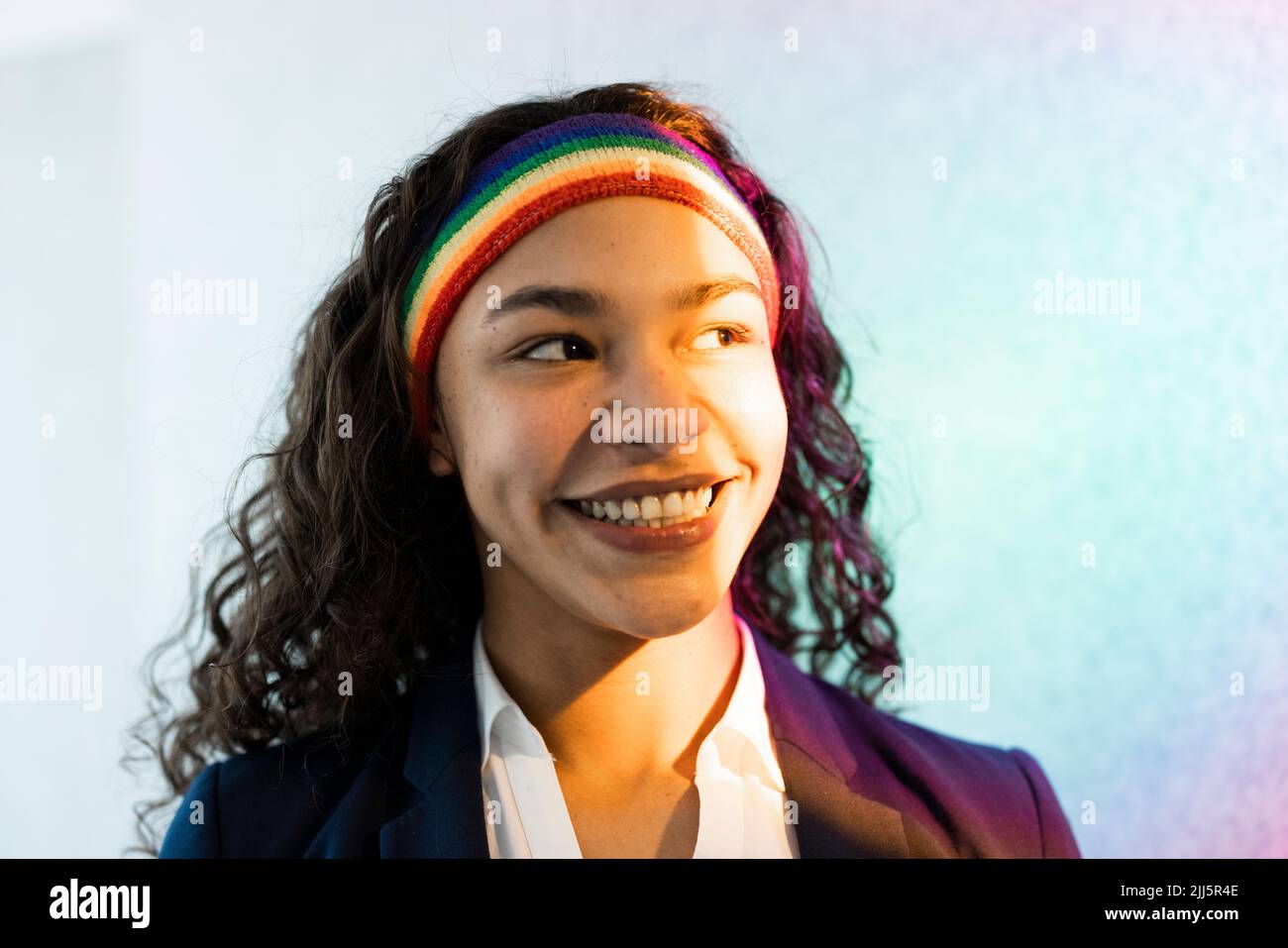 Happy young businesswoman with curly hair wearing multi colored headband Stock Photo