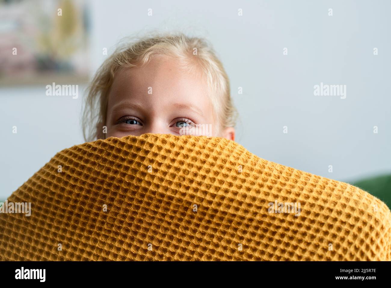 Girl hiding face under blanket at home Stock Photo
