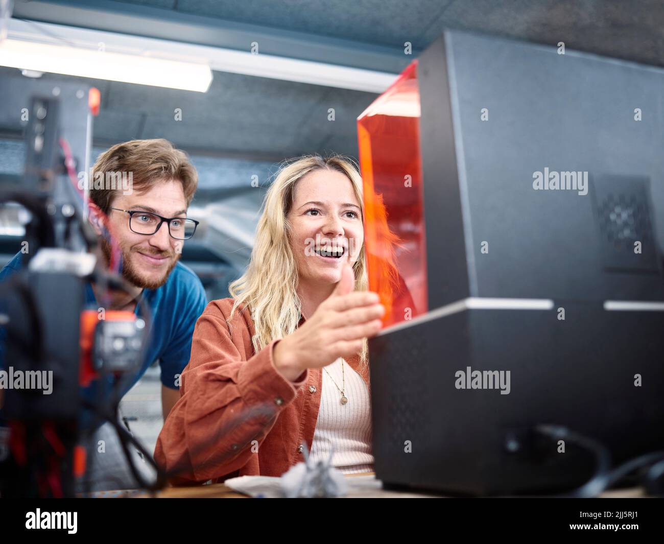 Happy technicians looking at SLA printer in workshop Stock Photo
