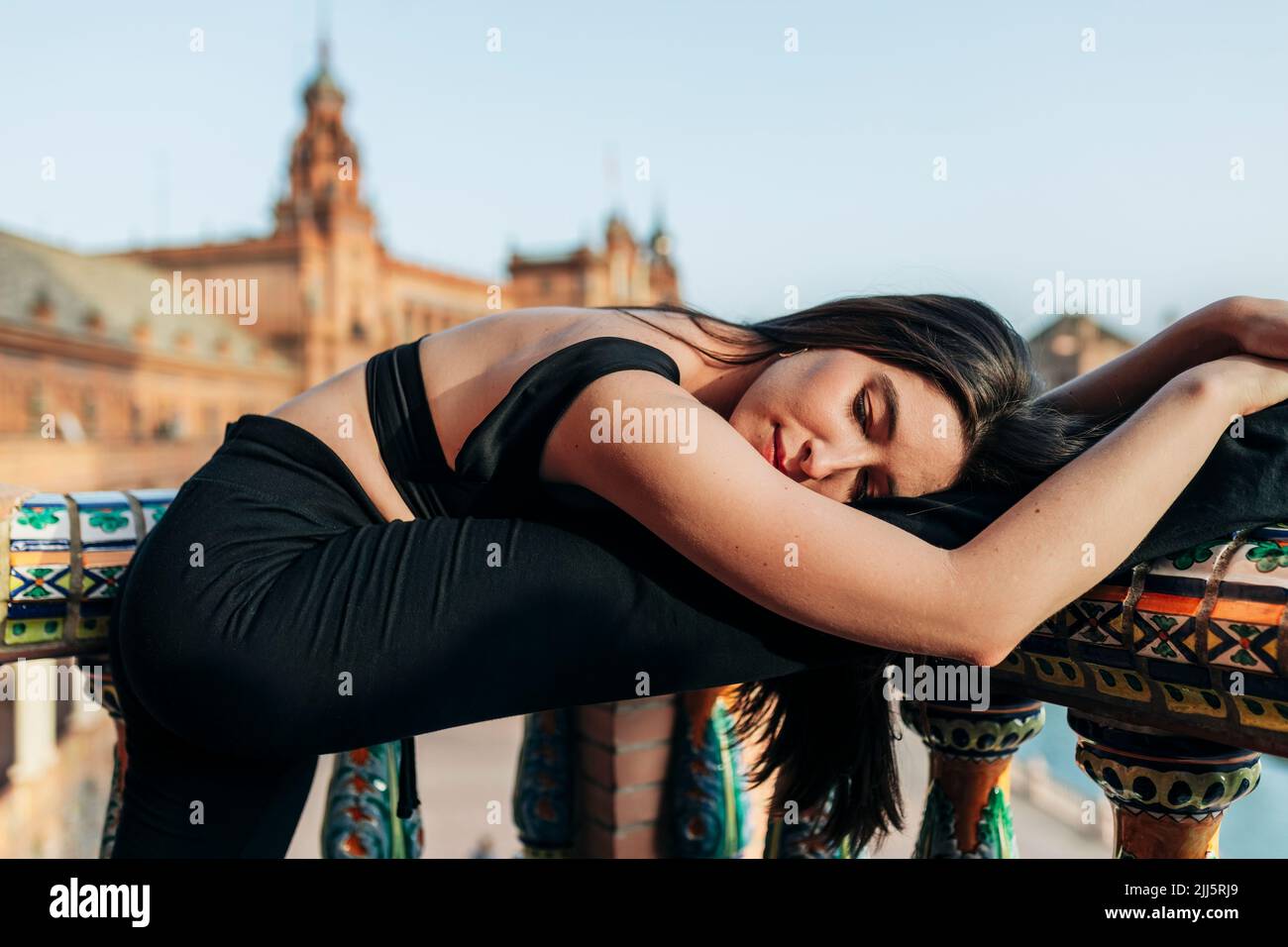 Ballet dancer with eyes closed leaning over stretched leg on railing Stock Photo