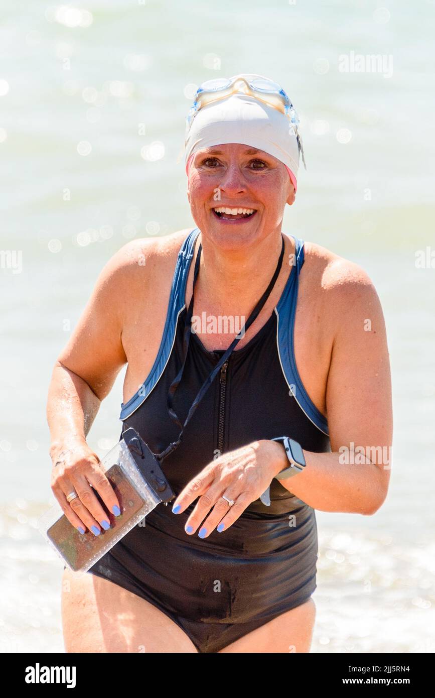 Brighton, UK. JULY 23, 2022.  Swimmer Jesse Barnes reacts to finishing the annual Round the Pier Swim at Brighton Palace Pier. Participants swim either to challenge themselves and for fun. A southwesterly breeze made the conditions a little choppy but the sun shone. Credit: Julia Claxton/Alamy Live News Stock Photo