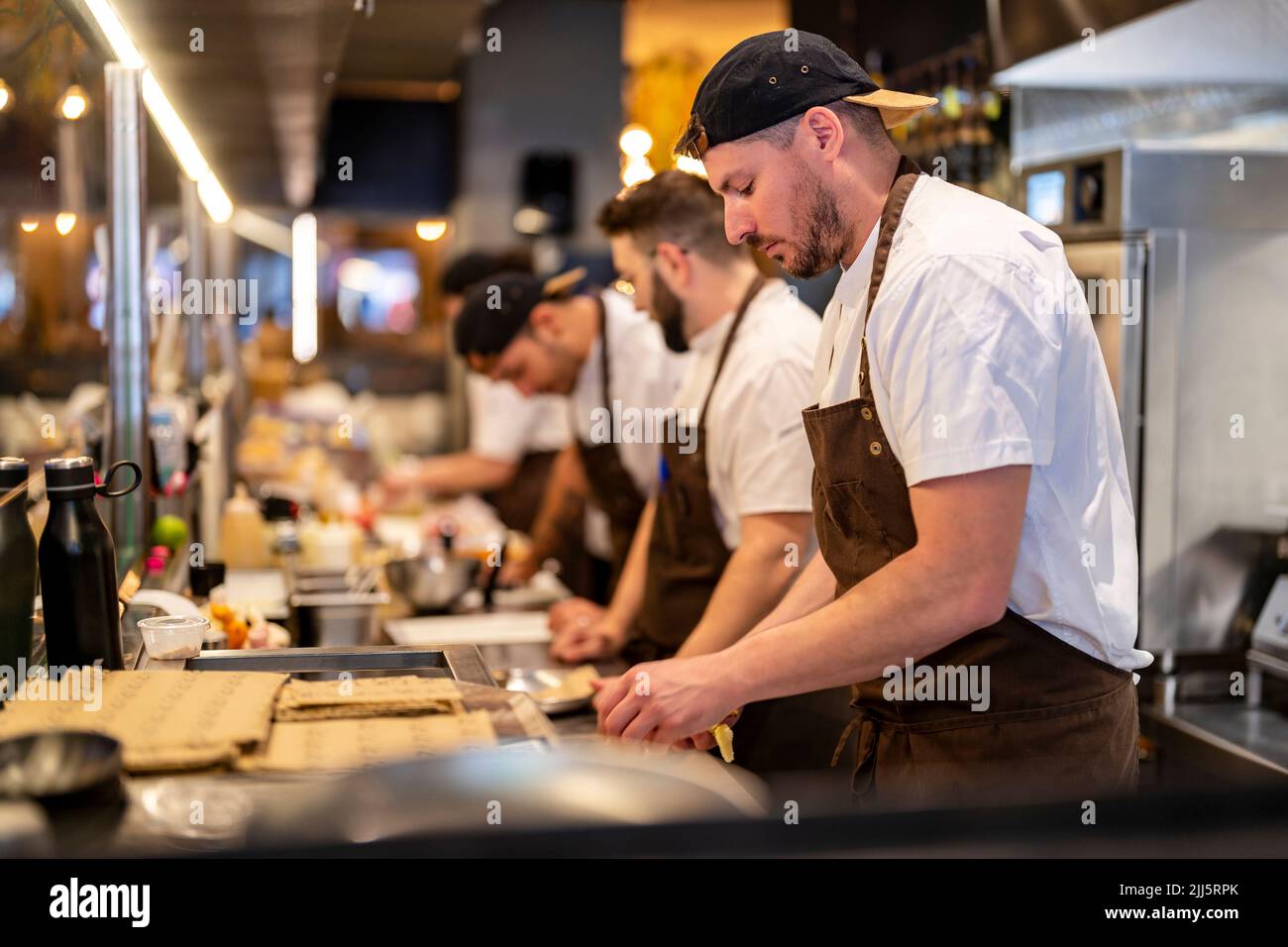 Chef standing by colleagues working at restaurant Stock Photo