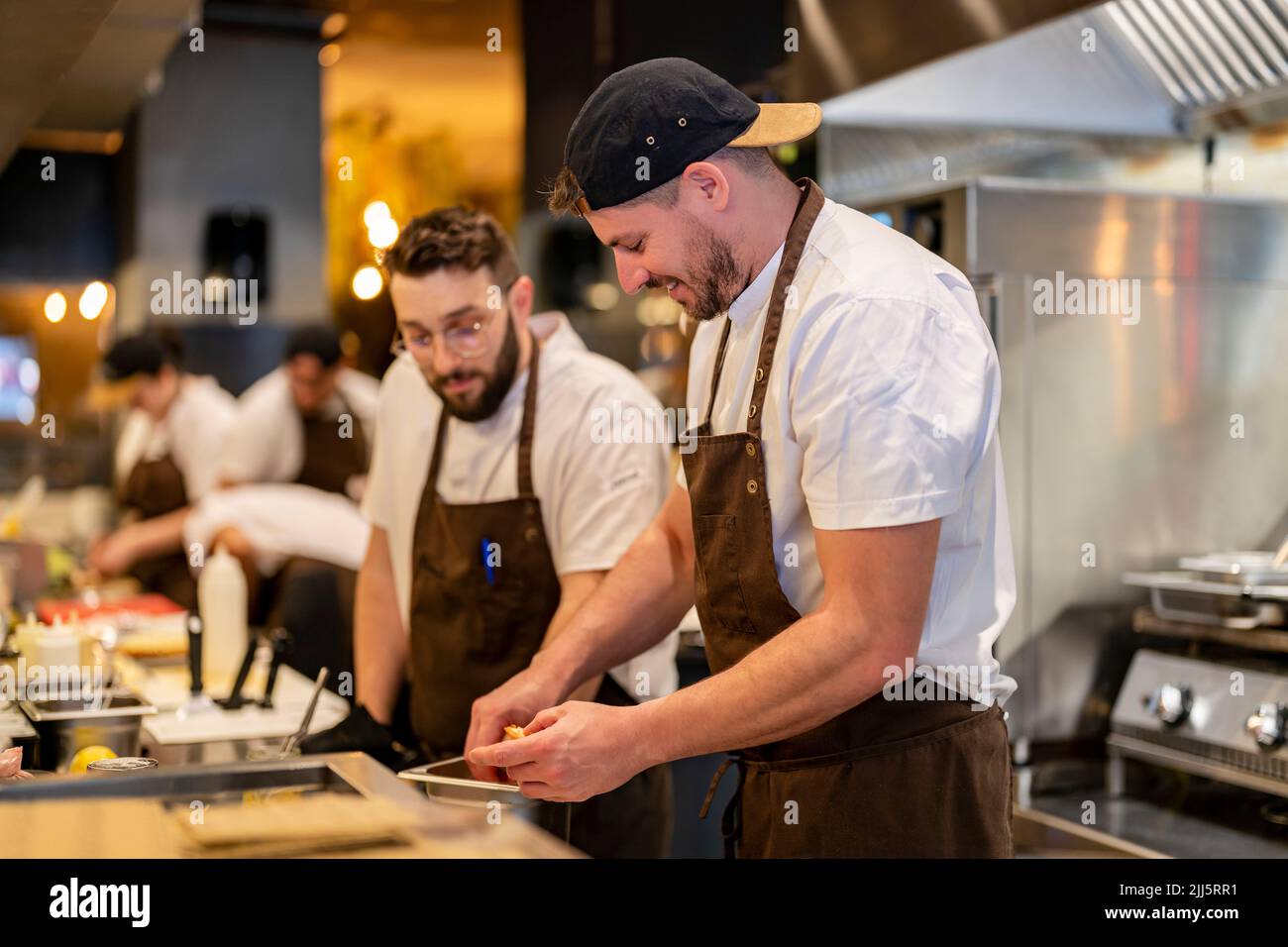 Chef preparing food standing by colleague at restaurant kitchen Stock Photo