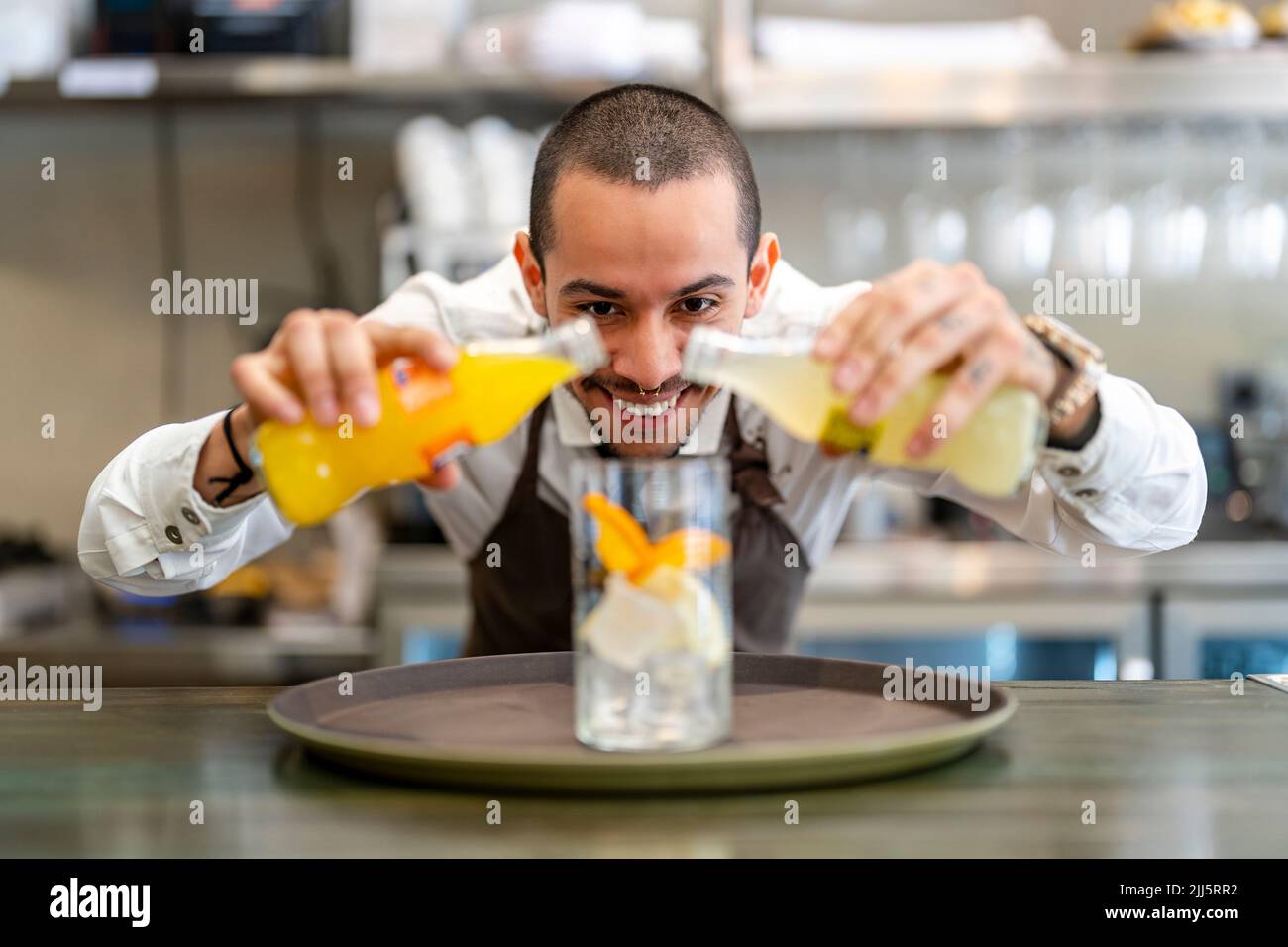 Smiling bartender pouring drink in glass Stock Photo