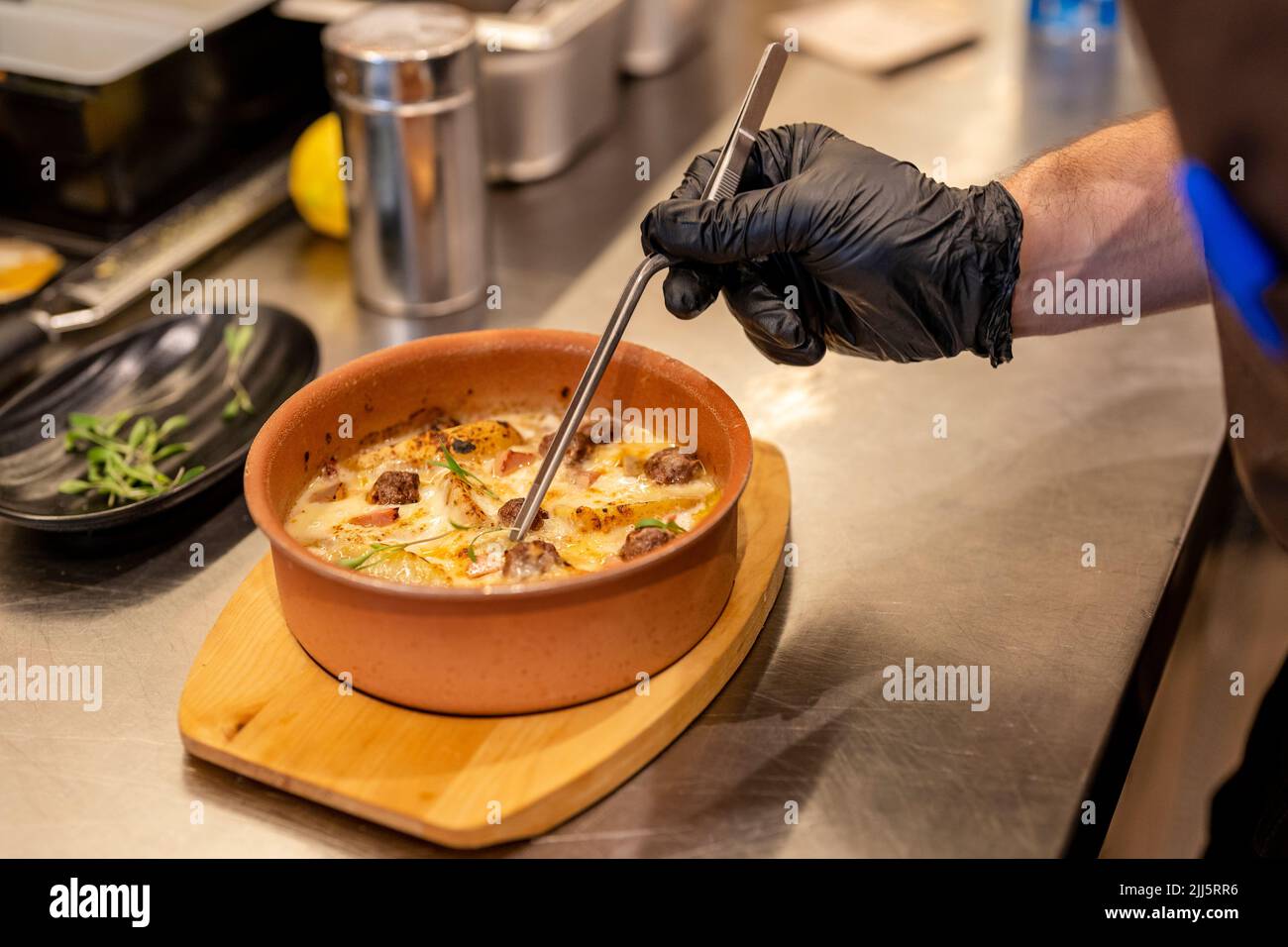 Hand of chef garnishing food with tweezers Stock Photo