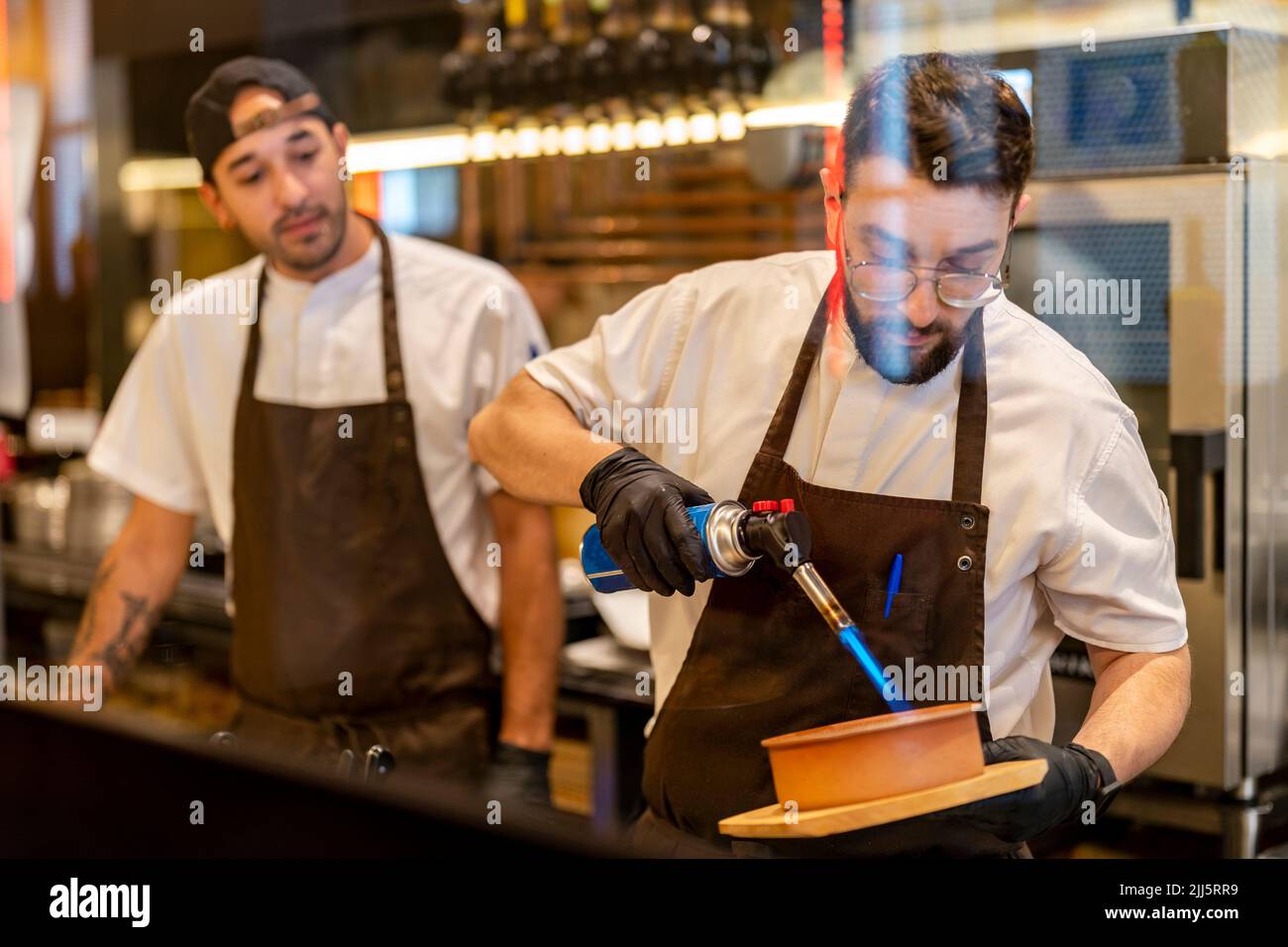 Chef using flaming torch standing with colleague at restaurant Stock Photo