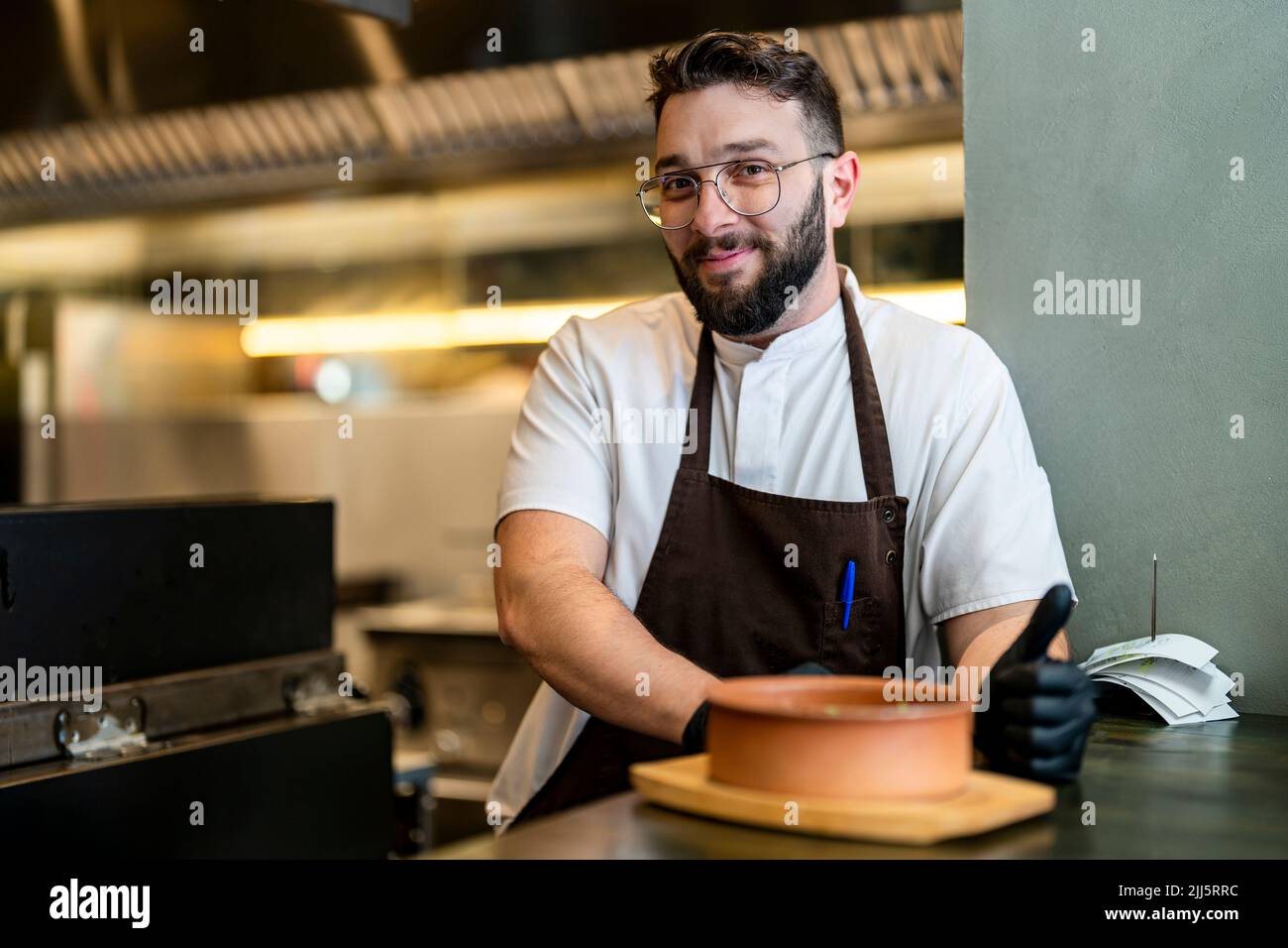 Smiling chef leaning on counter standing at restaurant Stock Photo