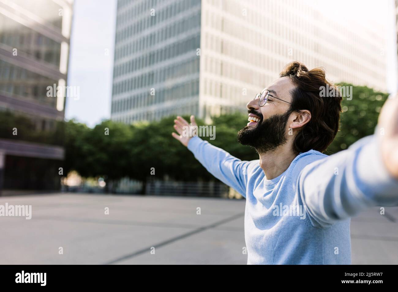 Happy man with arms outstretched in city Stock Photo