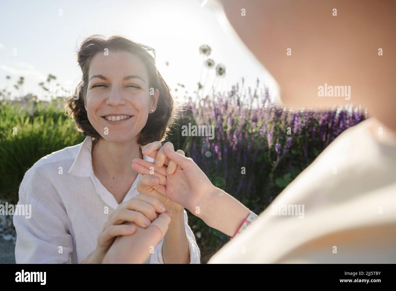 Cheerful mother holding hands with daughter at park Stock Photo