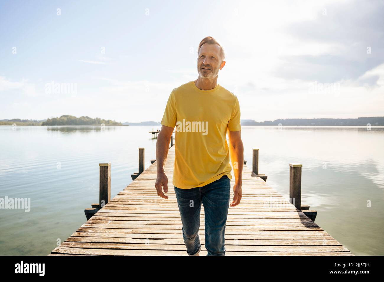 Mature man walking on pier at lake Stock Photo - Alamy