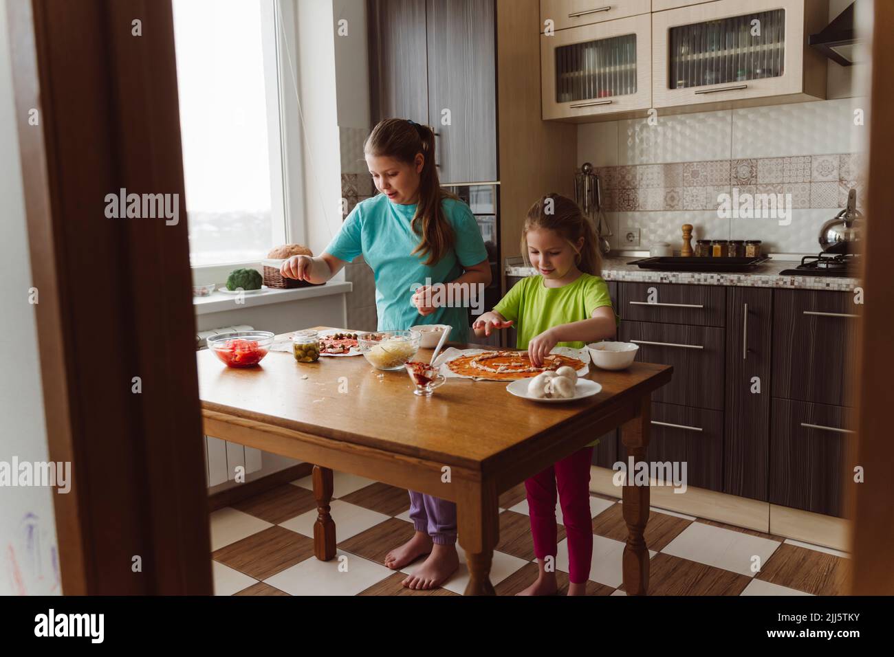 Siblings making pizza together in kitchen at home Stock Photo
